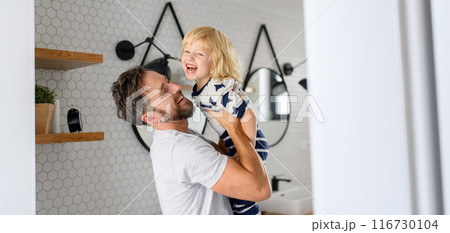 Father holding son in arms, standing in bathroom. Morning routine for young boy before going to preschool. Father holding son in arms, standing in bathroom. Morning routine for young boy before going to preschool. 116730104