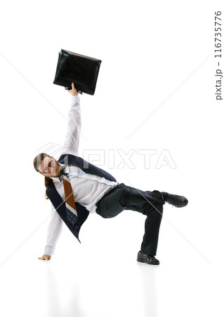 Breakdancer in business attire performs one-handed freeze while holding briefcase against white studio background. Flexibility. 116735776