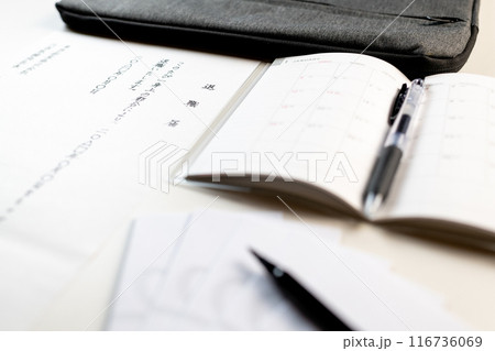 手書きで書かれた退職届の文面と新しいスケジュール帳と餞別用に準備されたポチ袋と筆ペン 116736069