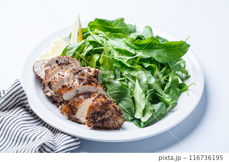 Green salad with grilled chicken breast on white plate, white background. 116736195