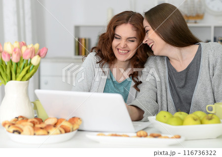 Two happy friends watching movie on laptop eating Two happy friends watching movie on laptop eating 116736322