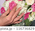 A womans hand with a French manicure touches a bouquet of flowers 116736829