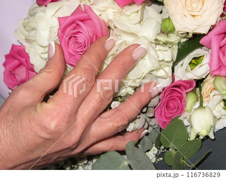 A womans hand with a French manicure touches a bouquet of flowers A womans hand with a French manicure touches a bouquet of flowers 116736829