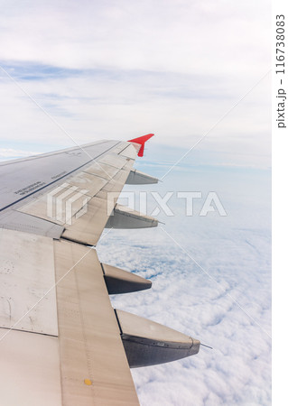 View from the airplane window at a beautiful cloudy sky and the airplane wing View from the airplane window at a beautiful cloudy sky and the airplane wing 116738083