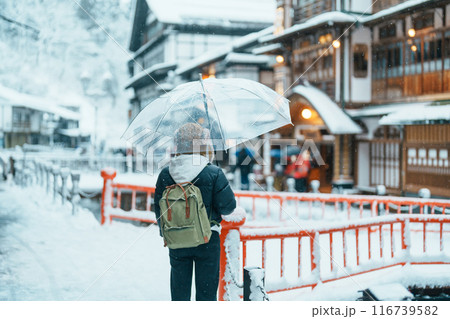 Woman tourist Visiting Ginzan Onsen in Yamagata, happy Traveler sightseeing Japanese Onsen village with Snow in winter season. landmark and popular for attraction in Japan. Travel and Vacation concept 116739582