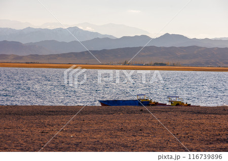 old pedal catamarans and boat on beach of mountain lake at sunny autumnal afternoon 116739896