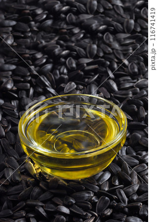 Organic sunflower oil in a glass bowl with sunflower seeds, close-up 116741419