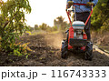 Farmer Using Rotary Tiller on a Plowed Field at Dawn 116743333