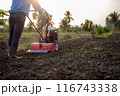 Farmer Using Rotary Tiller on a Plowed Field at Dawn 116743338