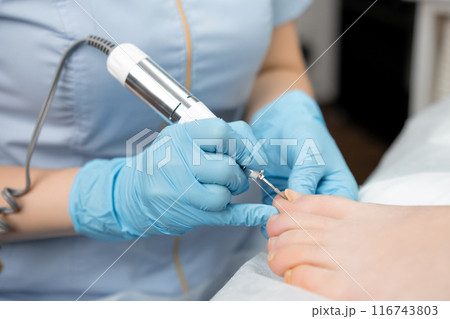 Podologist doing professional medical pedicure to young woman in the clinic. 116743803