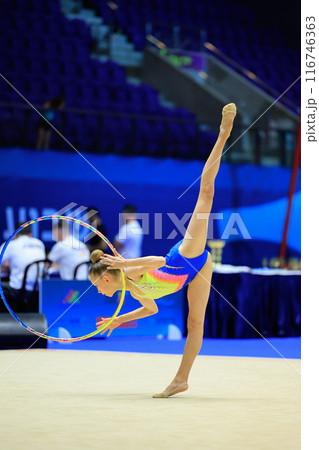 An artistic athlete specializing in rhythmic gymnastics performs a routine using a hoop An artistic athlete specializing in rhythmic gymnastics performs a routine using a hoop 116746363