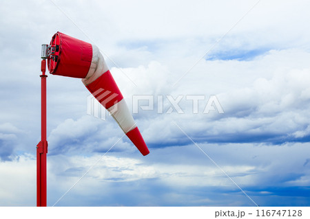 Red and white weather vane and dramatic cloudy sky. Red and white weather vane and dramatic cloudy sky. 116747128