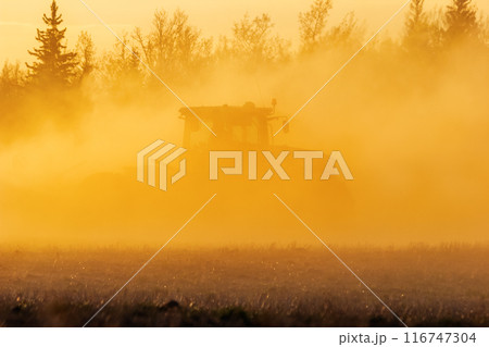 Silhouette of a tractor working in the field in dust, golden sunset. Silhouette of a tractor working in the field in dust, golden sunset. 116747304