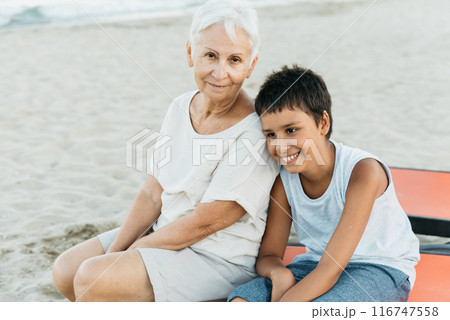 summer vacation at sea. Boy and senior woman at seaside. Grandmother with grandchild are resting on sea, running on beach having fun at summer holiday. Active parents, people activity with children. 116747558