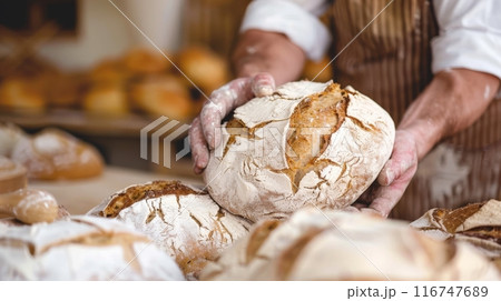 Baker holding freshly baked rustic bread in a bakery, close-up. Artisan baking concept 116747689