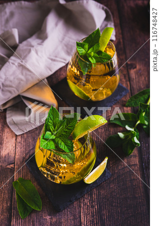 Summer detox drink with tea, lime and mint in glasses on the table vertical view Summer detox drink with tea, lime and mint in glasses on the table vertical view 116748427