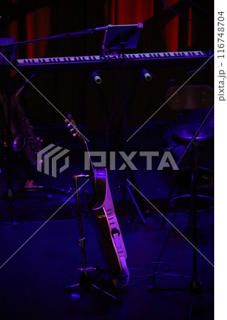 開演前の薄暗いライブハウスのステージに置かれたギターと電子ピアノ 開演前の薄暗いライブハウスのステージに置かれたギターと電子ピアノ 116748704