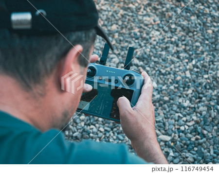 A closeup shot of a man, holding and operating a drone remote control joystick 116749454