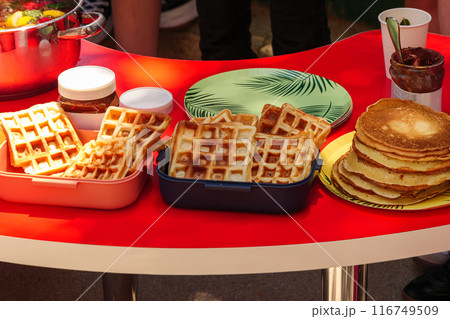 A picnic table with waffles, pancakes, and chocolate spread. A picnic table with waffles, pancakes, and chocolate spread. 116749509