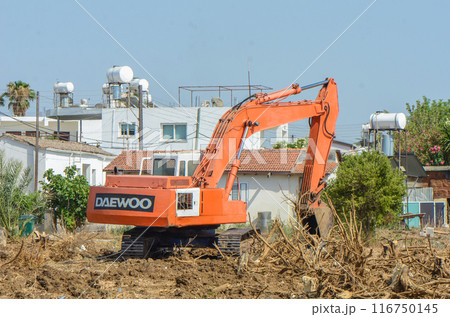 Gazeveren Cyprus 03.07.2024 - excavator uproots the roots of orange trees 116750145
