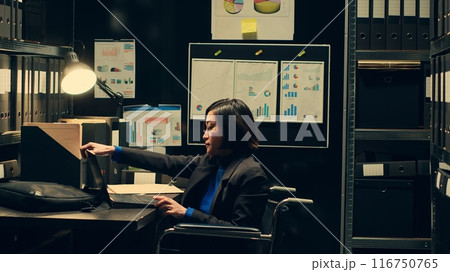 Law agent reviewing classified documents in archive room, searching for important clues from forensic evidence. Wheelchair user categorizing archived materials to facilitate investigation. Camera A. 116750765