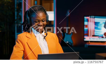 Young woman participating in online debate forums or academic competitions to learn case studies relevant to university coursework. African american girl listening to web webinar. Camera A. Young woman participating in online debate forums or academic competitions to learn case studies relevant to university coursework. African american girl listening to web webinar. Camera A. 116750767