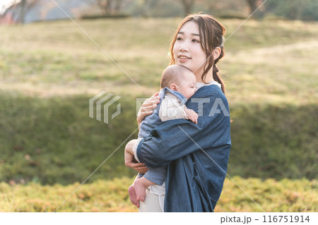 秋の公園を赤ちゃんを抱っこして散歩するママ（親子・母子・出産・産後） 116751914