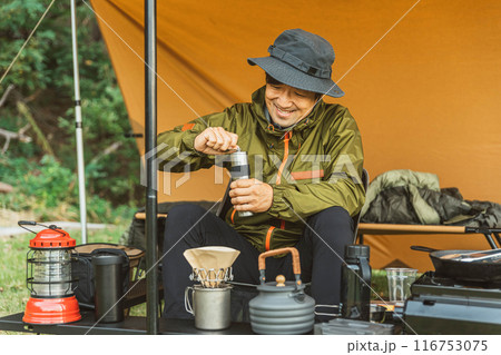 キャンプ場でソロキャンプする若い男性キャンパー（コーヒーミル） 116753075