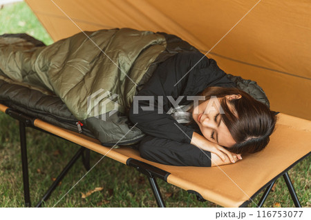 キャンプ場で寝袋・シュラフで寝る若い女性キャンパー（睡眠） 116753077