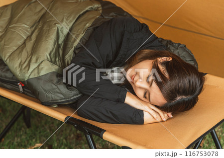 キャンプ場で寝袋・シュラフで寝る若い女性キャンパー(睡眠) キャンプ場で寝袋・シュラフで寝る若い女性キャンパー(睡眠) 116753078