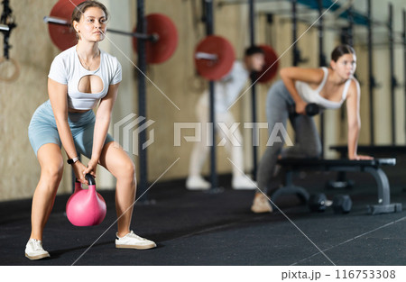 Young woman training with kettlebell in gym 116753308