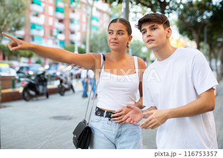 Positive tourist couple walking around foreign city on summer day, pointing at sights Positive tourist couple walking around foreign city on summer day, pointing at sights 116753357