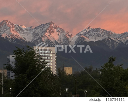 Sunset Over Snowy Mountain Peaks Behind Urban Skyline Sunset Over Snowy Mountain Peaks Behind Urban Skyline 116754111