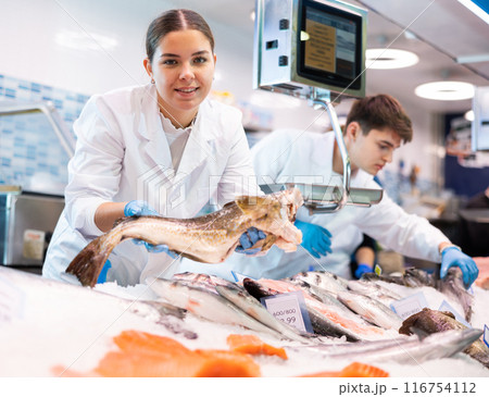 Portrait of saleswoman offering fresh fish atlantic cod at shop Portrait of saleswoman offering fresh fish atlantic cod at shop 116754112
