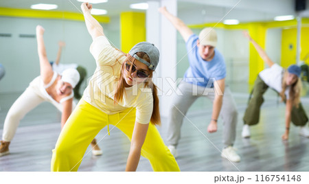 Excited positive teenage dancers having fun and learning modern dance during class in modern hall 116754148