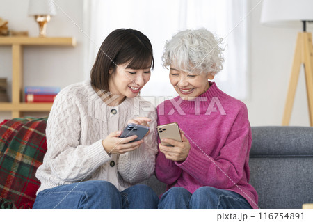 スマートフォンを持って話すシニア女性と若い女性 116754891