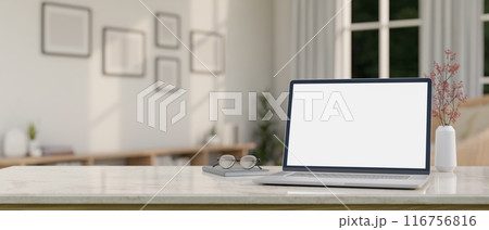 A laptop computer mockup, eyeglasses, and a book on a white marble table in a minimal white room. A laptop computer mockup, eyeglasses, and a book on a white marble table in a minimal white room. 116756816