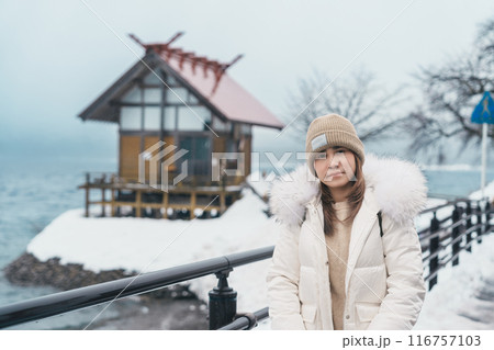 Woman tourist sightseeing Kansa Shrine and Lake Tazawa in winter. Traveler travel in Semboku city, Akita Prefecture, Japan. Landmark for tourist attraction in Tohoku region. Japan travel and vacation 116757103