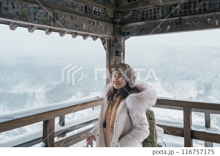 Woman tourist sightseeing view of village with snow in winter from mountain viewpoint of Yamadera temple or Risshakuji temple located in Yamagata City, in Yamagata Prefecture, Tohuku, Japan 116757175