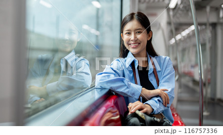 An attractive Asian woman sitting on a seat in a sky train with her backpack, commuting somewhere. 116757336