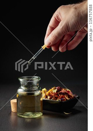 Dropping essential oil or herbal tincture into a small bottle. 116757888