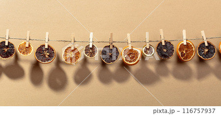 Orange, lemon and lime slices are dried on a line. 116757937