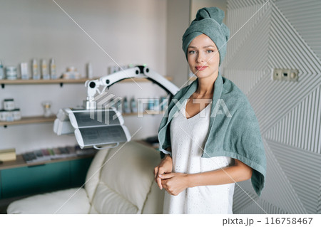 Portrait of pretty beautiful young woman in spa towel standing posing looking at camera after washing hair in beauty salon with casual and relaxed atmosphere. Beauty and hair styling concept 116758467