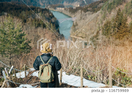 Woman tourist sightseeing View of Japan local train with Tadami river and bridge. Traveler travel at Tadami Railway Line in Mishima Machi, Aizu, Fukushima Prefecture, Japan. Landmark and iconic spot 116759989