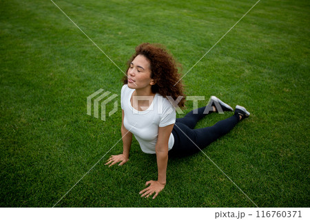 Beautiful curly girl warms up on the sports ground Beautiful curly girl warms up on the sports ground 116760371
