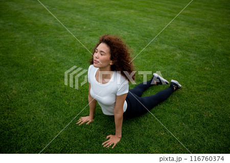 Beautiful curly girl warms up on the sports ground 116760374