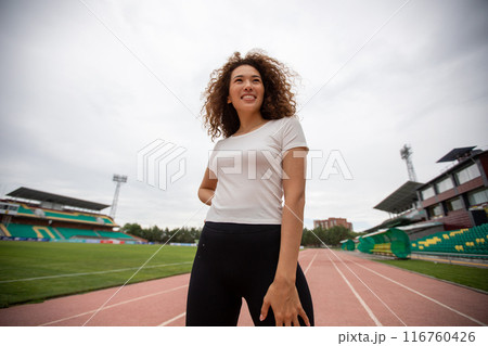 Beautiful curly girl warms up on the sports ground Beautiful curly girl warms up on the sports ground 116760426