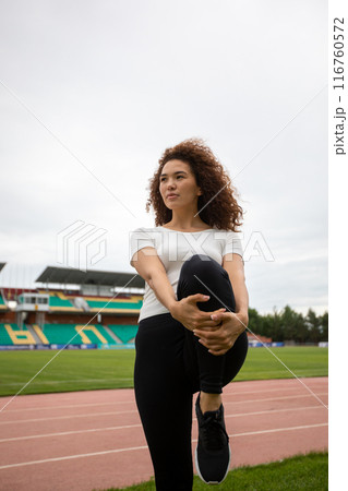 Beautiful curly girl warms up on the sports ground 116760572