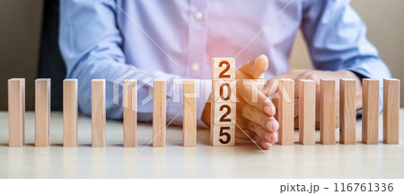 Businessman hand Stopping Falling of 2025 wooden Blocks. Business, Risk Management, Insurance, Resolution, strategy, solution, goal, New Year New You and happy holiday concepts Businessman hand Stopping Falling of 2025 wooden Blocks. Business, Risk Management, Insurance, Resolution, strategy, solution, goal, New Year New You and happy holiday concepts 116761336