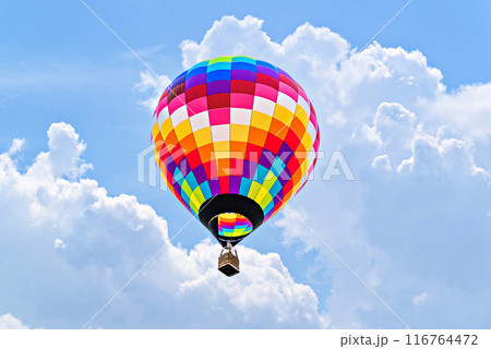 Colorful hot air balloon flying over blue sky with white clouds Colorful hot air balloon flying over blue sky with white clouds 116764472